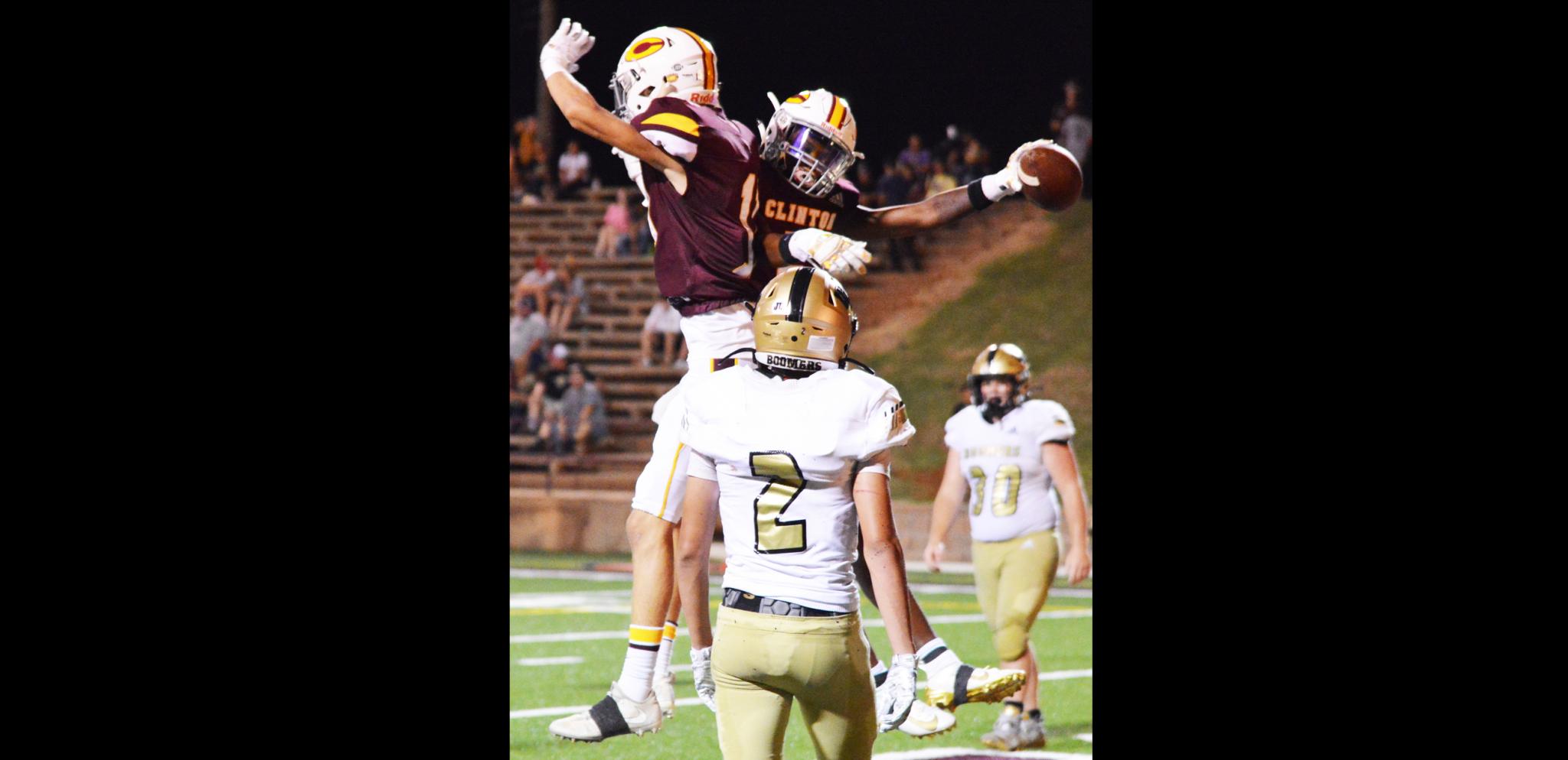 Clinton wide receivers Ty Newcomb, left, and A.T. Bryson, right, jump into the air to celebrate Bryson's touchdown catch against Woodward.