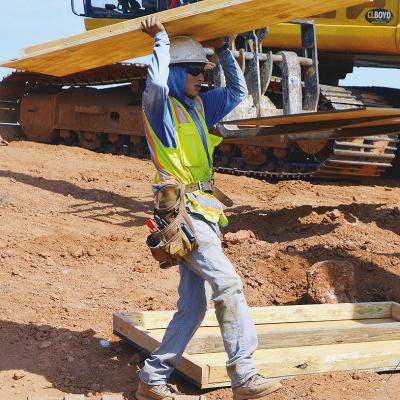 Antonio Garnica carries the next panel to create a box frame for a future concrete support beam Wednesday during construction on Red Wheat Drive. CDN | Christian Jacobsen