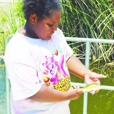 Jazzlyn Douglas shows off the fish she caught moments before at Acme Brick Park. CDN | Christian Jacobsen