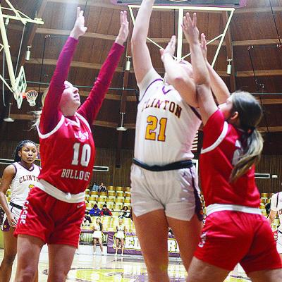 No. 21 Rhylee Rodebush goes up for a layup between two defenders during Clinton’s basketball home game Tuesday against Cache. Clinton’s Ethan Lofland takes a jump shot over a Cache defender during the Reds’ home game Tuesday against the Bulldogs.