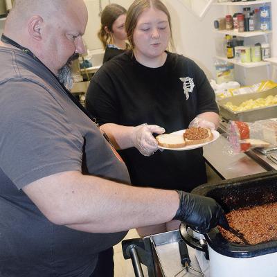 Jules Collins, left, and Abbey Shields prepare and serve a sloppy joe dinner Thursday at the Mission House kitchen. The kitchen served more than 80 people for dinner. CDN | Christian Jacobsen