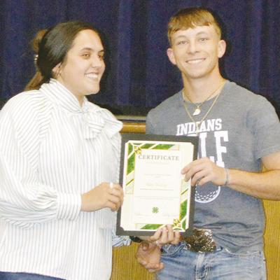 Ashlyn Hunter, left, awards Nate Hickey the Custer County 4-H Scholarship at the Arapaho-Butler Senior Awards ceremony at the auditorium. CDN | Christian Jacobsen