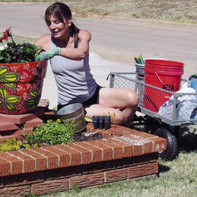 Montie Adair enjoys the recent warm weather by planting flowers at her home on Redstone Drive. CDN | Christian Jacobsen