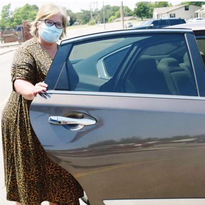 CDN |Litzy Silos Janalyn Taylor, the Nance Elementary School principal, opens the door to a car. She is demonstrating the new method that NES will be using for the car line. No parents will get out of their cars. NES staff will be coming to one of the two School drop-off procedures given