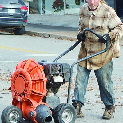 Jason Theb uses a blower to remove leaves piled up in the street Wednesday morning at the intersection of Sixth Street and Avant Avenue CDN | Micah Ashcraft