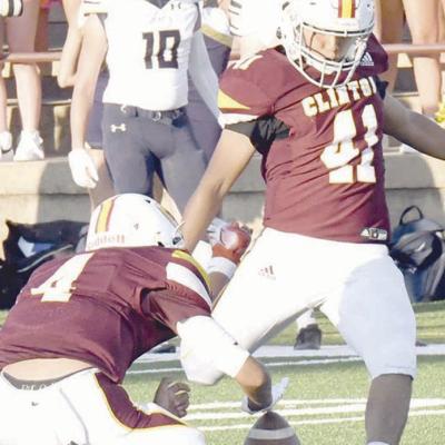 Sammy Velez kicks the football for Clinton while Talen Smith holds the ball in place. CDN | John Kinsey Sammy Velez kicks into his senior year
