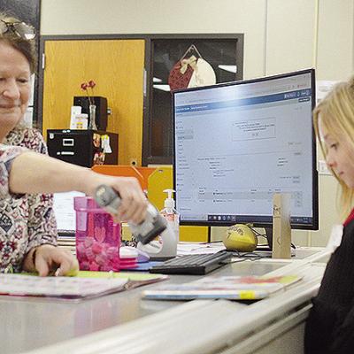 Nance Elementary School Librarian Sharon Harl, left, helps kindergartener Kezli Cox check out some new books Tuesday afternoon, on the first day of the new school semester. CDN | Micah Ashcraft