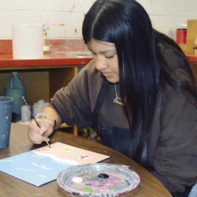 Brenda Vinaja paints shells and sand dollars onto her beach abstract art piece at Clinton High School. CDN | Christian Jacobsen