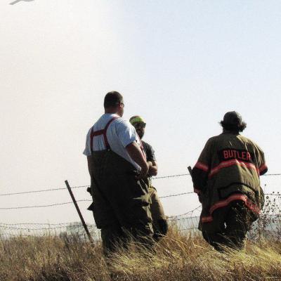 Area firefighters Isac Shephard, Cody Jeffrey, and Joel Barnett stand at the ready, as a “super scooper” plane flies to Foss Lake to refill Wednesday afternoon near Butler. CDN | Christian Jacobsen