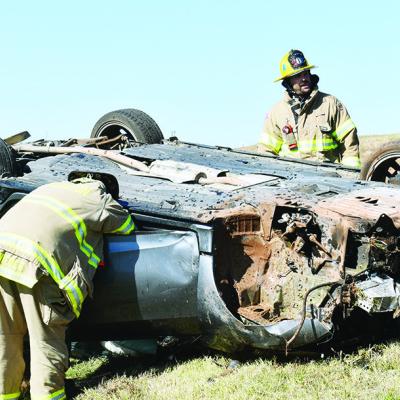 Around 11 a.m. Tuesday morning a Honda Civic was left inverted on the grass after an accident with a semi-truck by the westbound mile marker 62 exit ramp. Firefighters, from left, Colin Wieder, Lt. Justin Hill and Billy Gerstenkorn inspect the vehicle aft Collision with semi