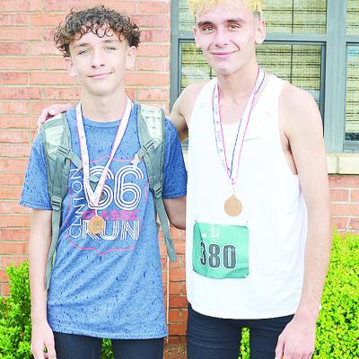 Brothers Bentlee Hernandez, left, and Xadrian Hernandez smile as they show off their gold medals after winning the 5K and 10K races of the recent Clinton Classic Run on Frisco Avenue. CDN | Sam Goodwyn