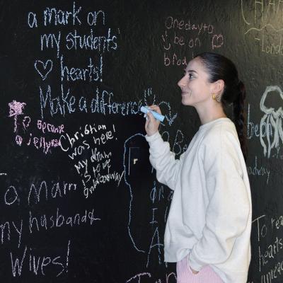 Miranda McLean adds positive notes to the wall of “The Spark Project” space on the corner of Frisco and Sixth Street. CDN | Christian Jacobsen