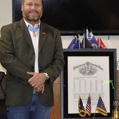Master Sergeant Earl Plumlee stands next to the new building charter for the MSG Earl Plumlee Post 4465 Tuesday in the Clinton VFW. CDN | Christian Jacobsen