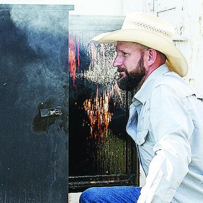 Dave Helch checks on his smoker last weekend during the rodeo at the Clinton Round-Up Club Arena. CDN | Sam Goodwyn