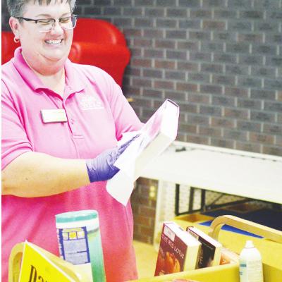 CDN | Collin Wieder Kathy Atchley, Public Services Coordinator for Western Plains Library System, cleans and sanitizes books in the quarantine room at the Clinton Public Library. Library adapts well during virus