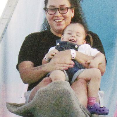 Vanessa Roque holds Nova Eaton as they slide down the Fun Slide at the Spring Carnival at Acme Brick Park. CDN | Christian Jacobsen