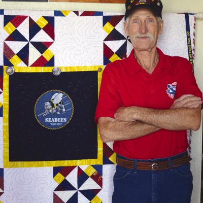 Mike Mapel stands in front of his Quilt of Valor, presented to him by the Cheyenne Senior Citizens Center, Monday at his home in Butler. CDN | Christian Jacobsen