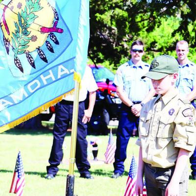 Clinton Boy Scout Troop 361 member Justin Tyler Schenewolf posts the Oklahoma state flag and prepares for a moment of silence followed by a prayer while Clinton Fire Department Lt. Dylan Abner, left, and firefighter Tyler Calvert watch during the American A time of reflection