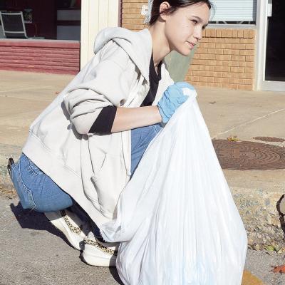 Senior Brylee Jones picks up trash left in the street as part of her Capstone community service on Frisco Avenue. CDN | Micah Ashcraft