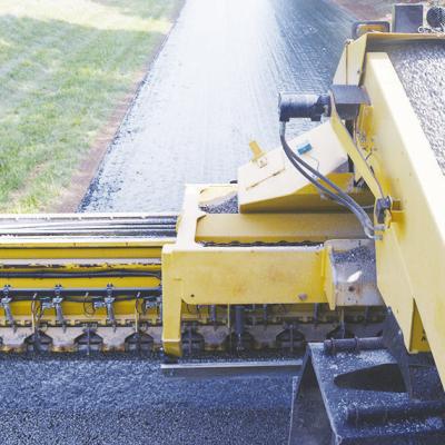 A Rock chipper spreads gravel on a layer of oil to become the first layer of a paved street at N. 2260 Road. CDN | Christian Jacobsen
