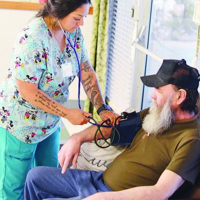 Elsa Villanueva, left, checks the blood pressure of Jimmy Burden Friday morning at River Valley Skilled Nursing and Therapy. CDN | Michael Maresh