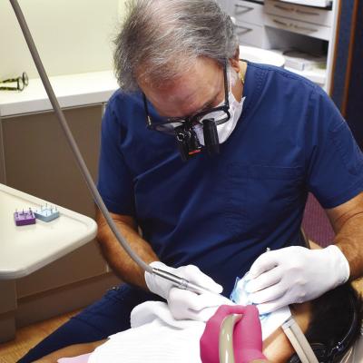 Dr. Floyd Simon Jr. works on Omar Nguyen’s teeth at his dental practice. CDN | Emily Stephens Dental care offered by Simon for 40 years
