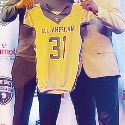 Clinton’s Zaedon Collins, right, accepts his game jersey from NFL vet Victor Butler, who also served as Collins’ defensive coordinator, prior to the All-Star Game. CDN | Courtesy photo