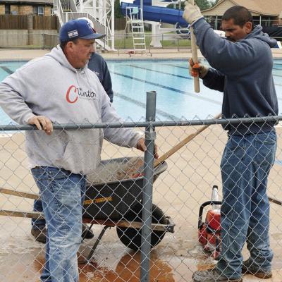 David Russell, left, and Robert Plaza replace and install a new fence post at the Clinton Swimming Pool. CDN | Christian Jacobsen