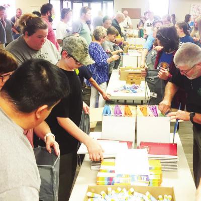 Members from several different Clinton churches work together filling backpacks for a school supply giveaway event to be held Wednesday. Churches collaborate on free school supplies