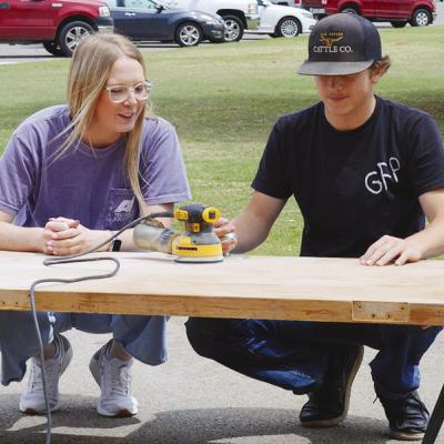 Alexia Newman guides Sy Foster while he sands a wooden door at Clinton High School. CDN | Christian Jacobsen