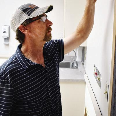 Jeff Hunter of 66 Wood Products paints along a door jamb in the Clinton Regional Hospital. CDN | Caleb Blanchard City manager optimistic for hospital