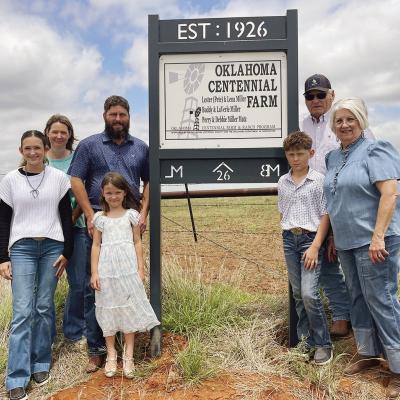 The Matz family, consisting of, from left, Kendall, Kyla, Kimber, Derek, Kellan, Perry, and Debbie Matz pose with the sign designating the Miller/Matz Farm as a historical landmark near Arapaho. CDN | Courtesy photo