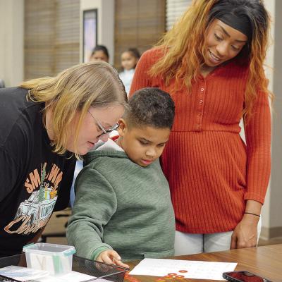 Nance Elementary School teacher Julie Adkinson, left, works on a lesson with her student Jordin Perez and his mother Carrie Perez during the Clinton Public Schools Board of Education’s monthly meeting Monday evening. CDN | Micah Ashcraft Nance Elementary School teacher Julie Adkinson, left, works on a lesson with her student Jordin Perez and his mother Carrie Perez during the Clinton Public Schools Board of Education’s monthly meeting Monday evening. CDN | Micah Ashcraft