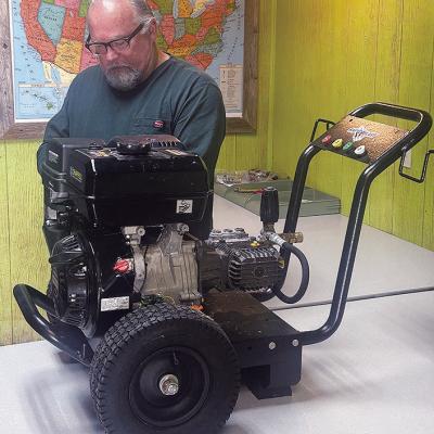 Rick Walker preps a pressure washer at Ranch Work Equipment for display at the Oklahoma City Farm Show. CDN | Christian Jacobsen