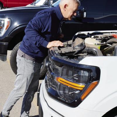 Kent Miller, a sales consultant with McKinsey Motors, looks over an engine at the auto dealership. CDN | Michael Maresh