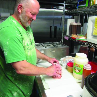 Lynn Klaassen loads up the meat to serve a Wooly Burger at Jigg’s Smokehouse. The Rt. 66 staple is going on the market. CDN | Angela Nichols Iconic eatery going up for purchase