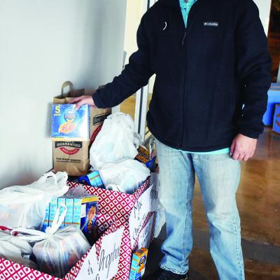 Eli Colston adds a box of mac and cheese to the box of food donations set to be given to the community for free. Edge food giveaway scheduled Sunday