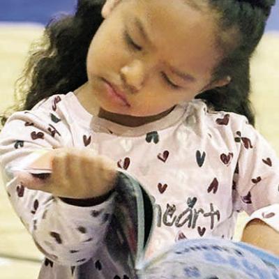 Nylah Mejia intensely scans the pages of the “Where’s Bluey?” book at the book fair. The search-and-find series has captured her full attention as she eagerly tries to locate the beloved character. CDN | Elisha Rangel Quest for Bluey