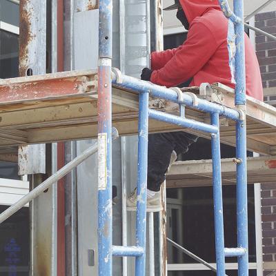 Edin Carrillo works to remove the rivets off the metal framework while repairing a pillar of the Clinton Public Library Wednesday morning, after a fire started within the pillar this past June. CDN | Micah Ashcraft