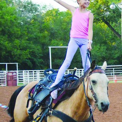 Josie Nichepor with her horse, Lizzy, practice trick riding moves Wednesday afternoon at the Clinton Rodeo Grounds. The Clinton Rodeo will take place tonight and tomorrow, with a scheduled parade at 10 a.m. tomorrow morning down Frisco Avenue. CDN | Chris