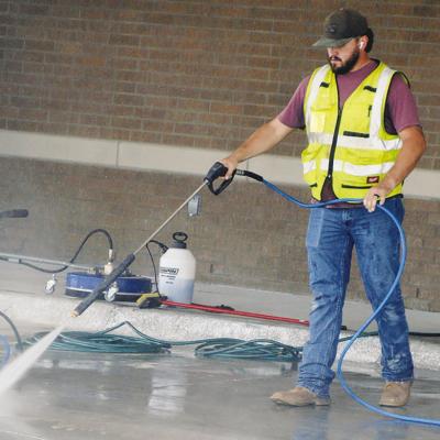Maxwell Murray pressure washes new concrete Thursday at the Oklahoma Highway Patrol Troop H Headquarters construction site. CDN | Christian Jacobsen