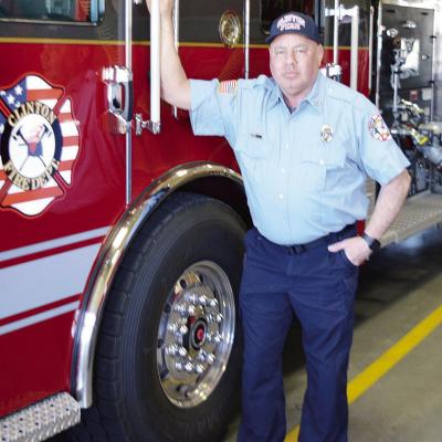 Clinton Firefighter John Denney stands next to a fire engine at the station. CDN | Michael Maresh
