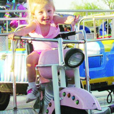 Andee Crumley rolls on her motorcycle in a “Cars” themed ride at last weekend’s Spring Carnival in Acme Brick Park. CDN | Christian Jacobsen