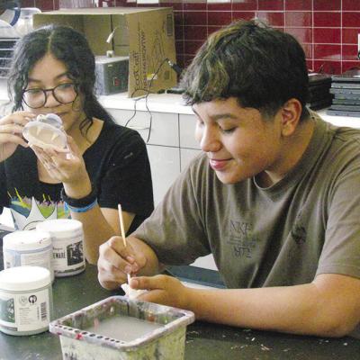 Valerie Pilloc, left, and Santiago Rodriguez Morquecho work on their big mouth art sculptures in class Tuesday at Clinton Middle School. CDN | Christian Jacobsen