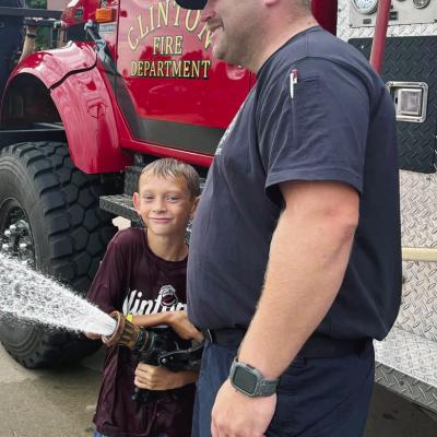 Wyatt Baily, left, is assisted by Clinton Fire Department’s Lt. Joe Williams as he tests out the fire hose at Washington Elementary. CDN | Courtesy photo