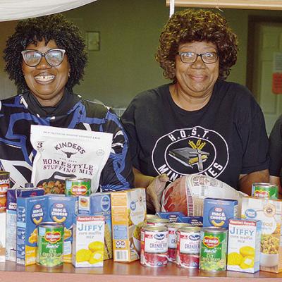 From left, Jeffrey Waffle, H.O.S.T. Ministries Pastor Wilma Jackson, Lynn Flanders, and Kendra Richardson show off the spread of food ready to be prepared ahead of the H.O.S.T. Ministries Church Christmas Free Community Meal, set for 11 a.m. to 1:30 p.m. 