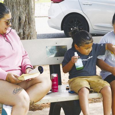 From left, Victoria Hernandez, Elise Martinez, and Evalina Martinez rest from the summer sun at the McLain Rogers Park Playground. CDN | Christian Jacobsen