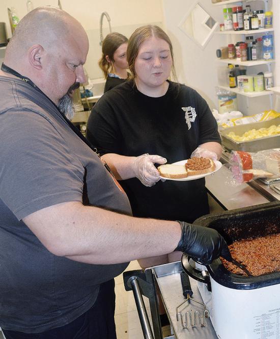 Jules Collins, left, and Abbey Shields prepare and serve a sloppy joe dinner Thursday at the Mission House kitchen. The kitchen served more than 80 people for dinner. CDN | Christian Jacobsen