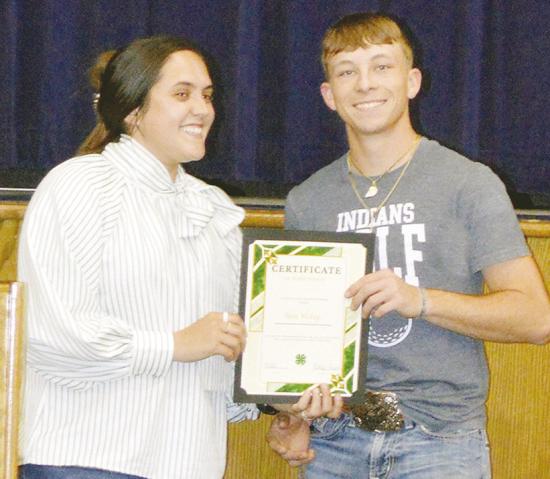Ashlyn Hunter, left, awards Nate Hickey the Custer County 4-H Scholarship at the Arapaho-Butler Senior Awards ceremony at the auditorium. CDN | Christian Jacobsen