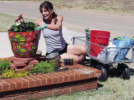 Montie Adair enjoys the recent warm weather by planting flowers at her home on Redstone Drive. CDN | Christian Jacobsen